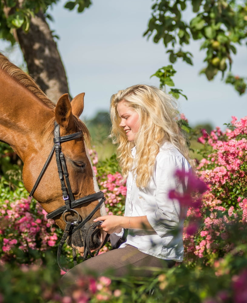 Forårsbillede af pige med sin hest, omgivet af lyserøde blomster. Foto: Majken Soelberg.