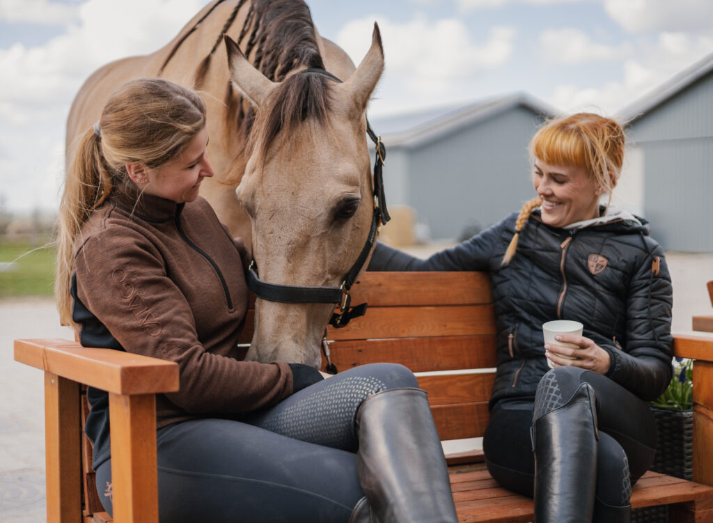 to-heste-veninder-drikker-kaffe-ved-stalden.