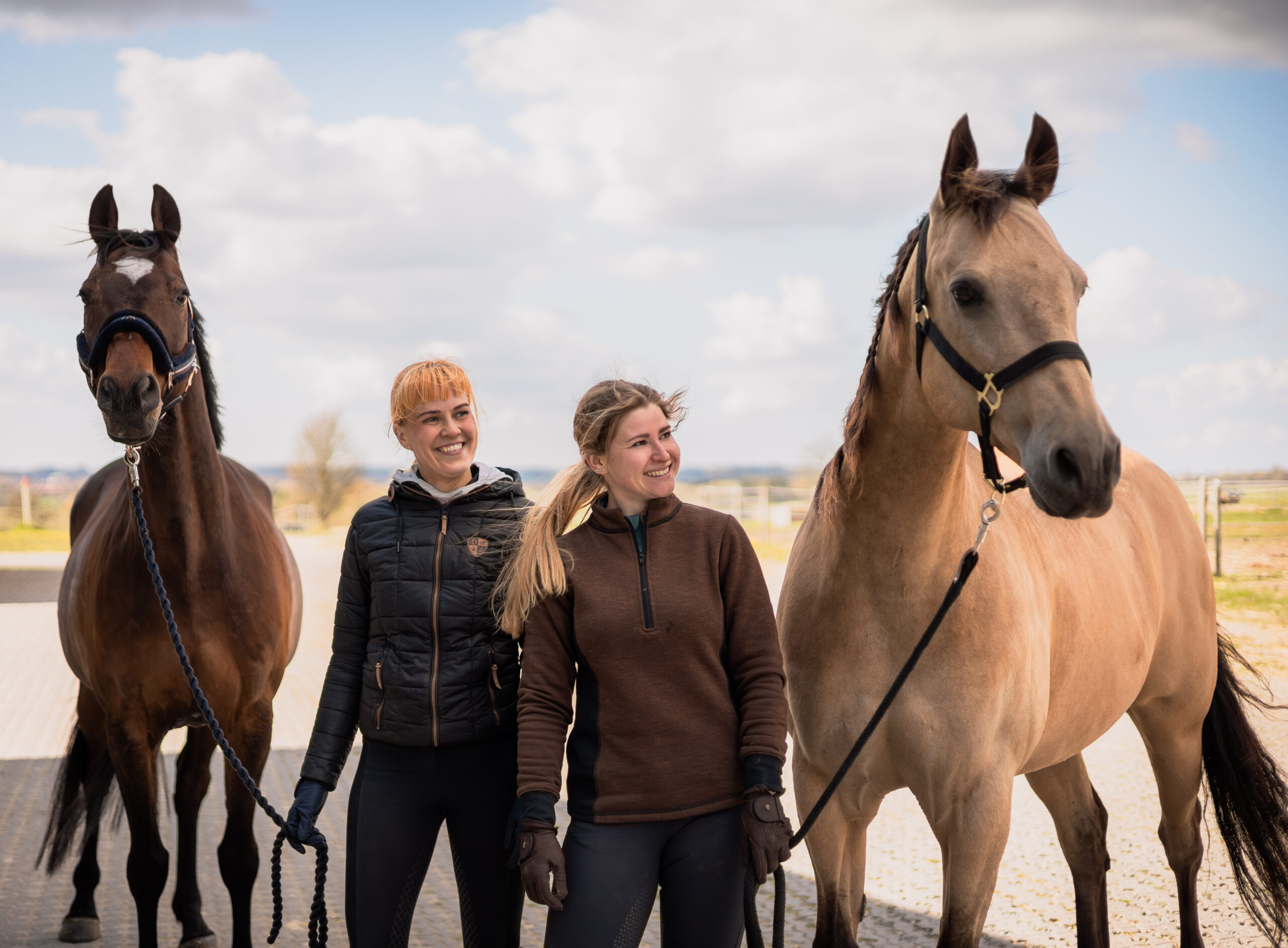 to-ryttere-traekkende-med-to-heste-glade-udenfor.